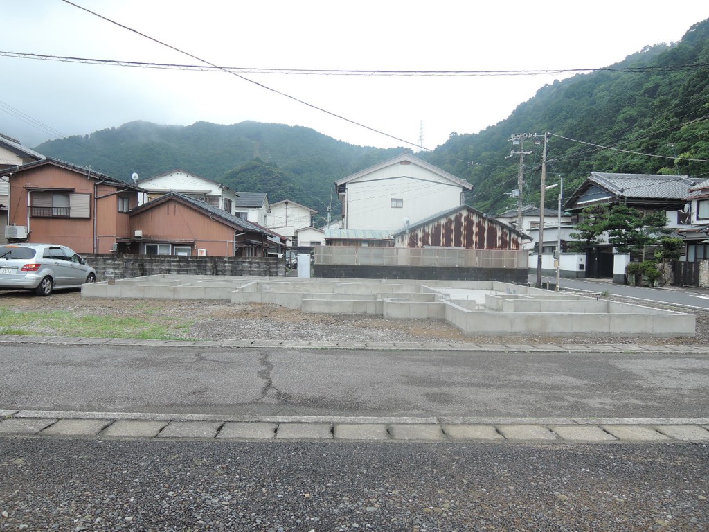 磐盾のコートハウス：道路越しに望む、型枠を外したコンクリート基礎の全景