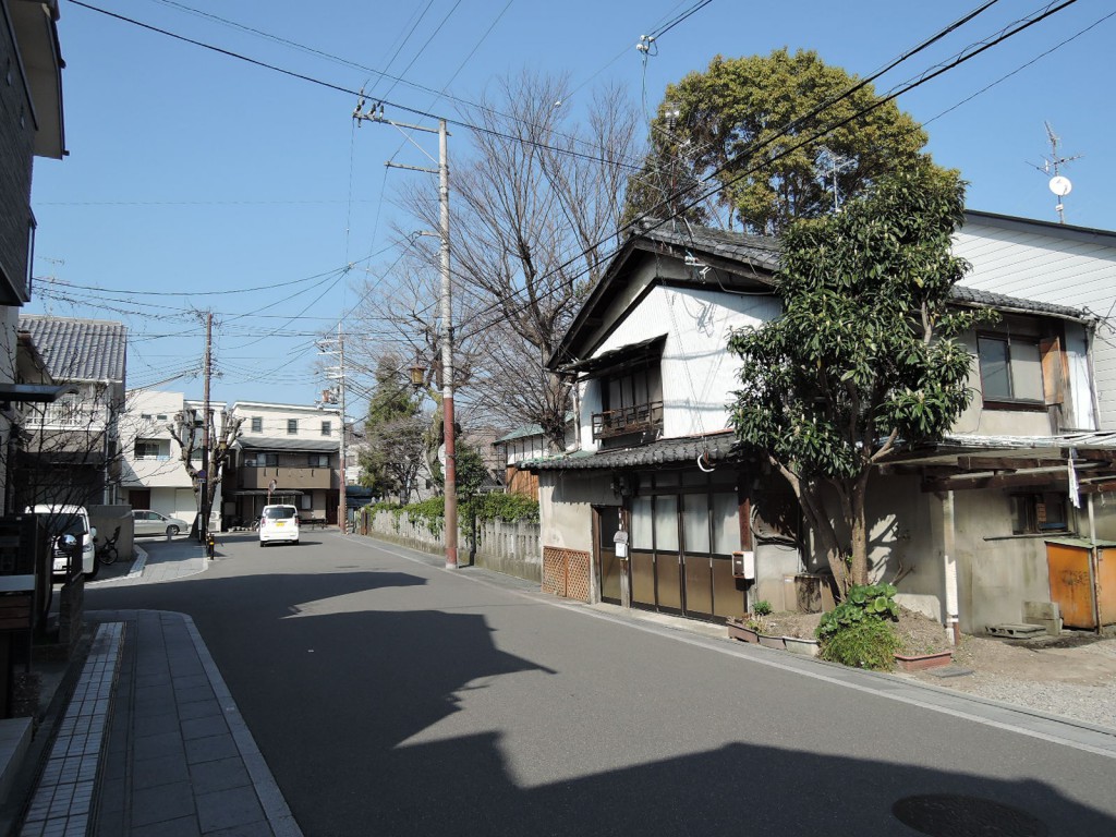 高槻のオフィス：計画地前の旧街道と、瓦屋根の建物や木々が並ぶ街並み