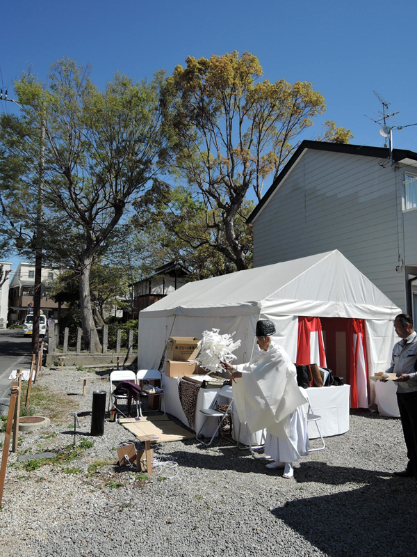 高槻のオフィス：青空と新緑の下、地鎮祭のテント前でお祓いをする神職