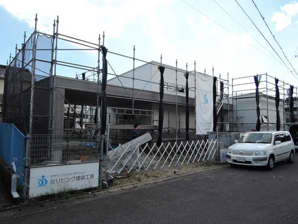 新宮佐野の平屋：白いサイディングの外壁と大きな庇が見える、足場に囲まれた外観