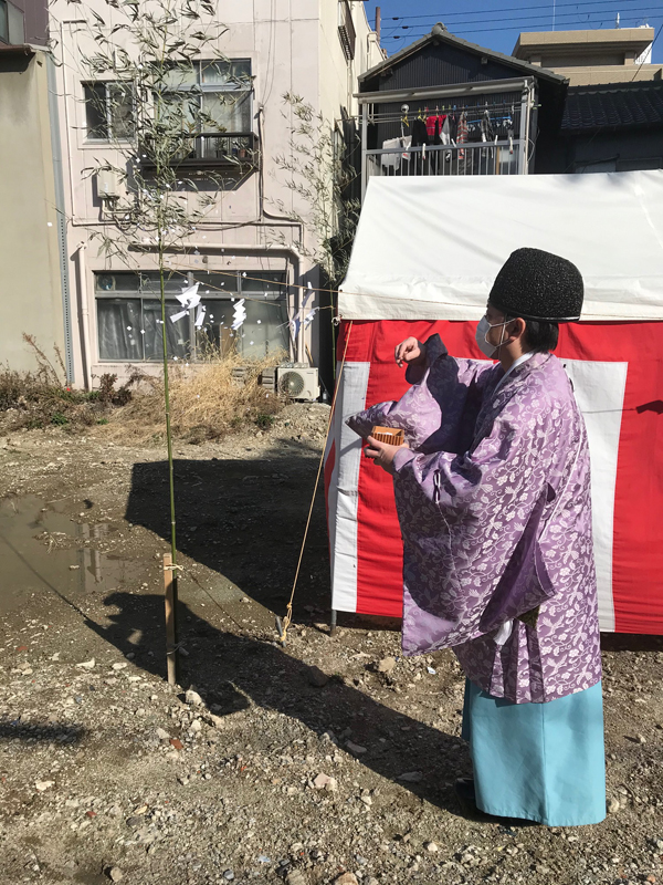 今里のガレージオフィス：紅白幕のテント脇で敷地を清める神職